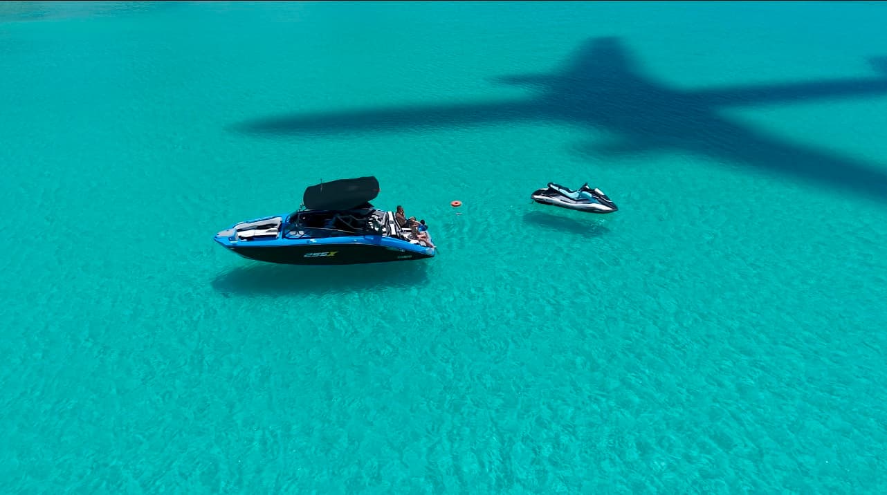 宮古島のボートチャーター - 透明度抜群のエメラルドグリーンの海に浮かぶボートとジェットスキーの空撮