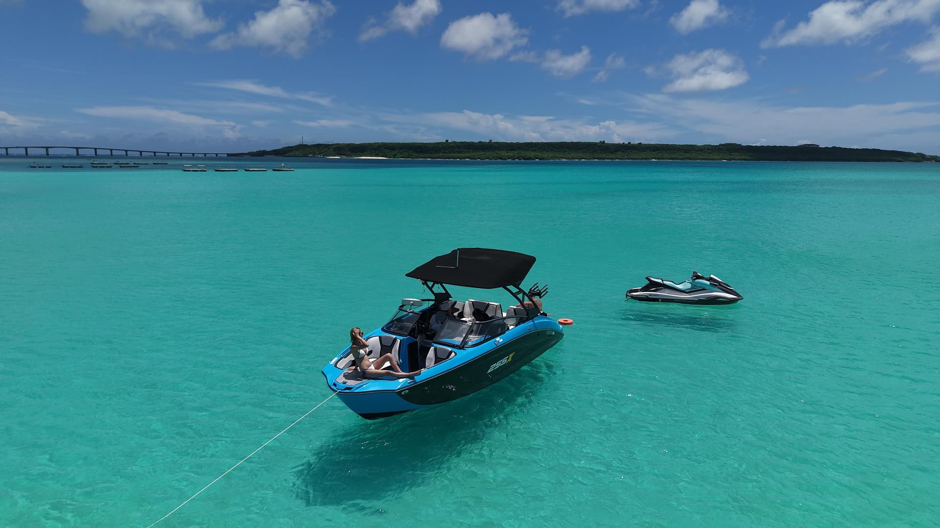 エメラルドグリーンの海に浮かぶ255Xボートとジェットスキー - 伊良部大橋を背景にした絶景