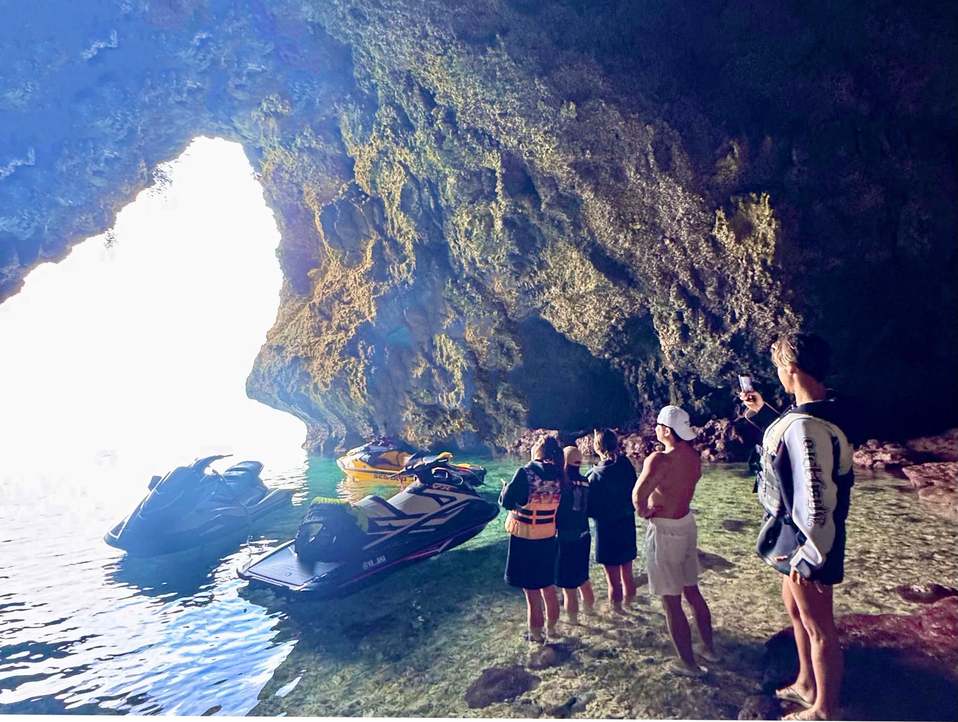 宮古島の秘境ツアー - 洞窟内に停泊したジェットスキーと観光客の様子
